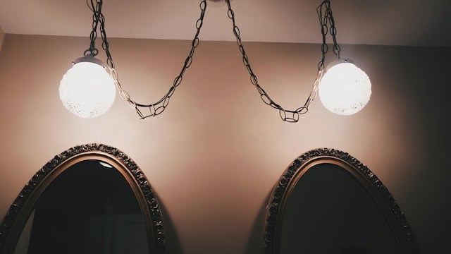 two oval mirrors with lights above